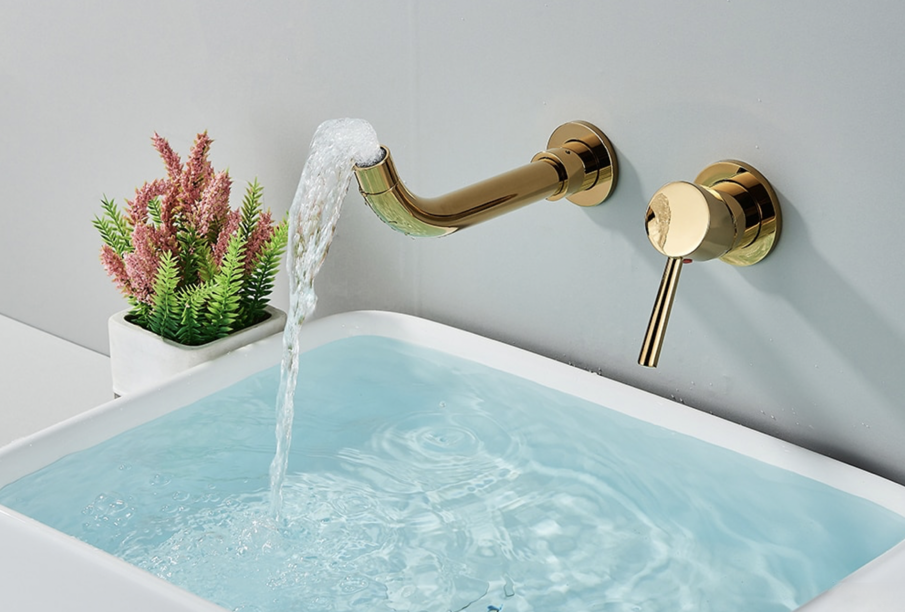 Rubinetto a parete dorato per lavabo SG1520 in uso su un lavabo bianco